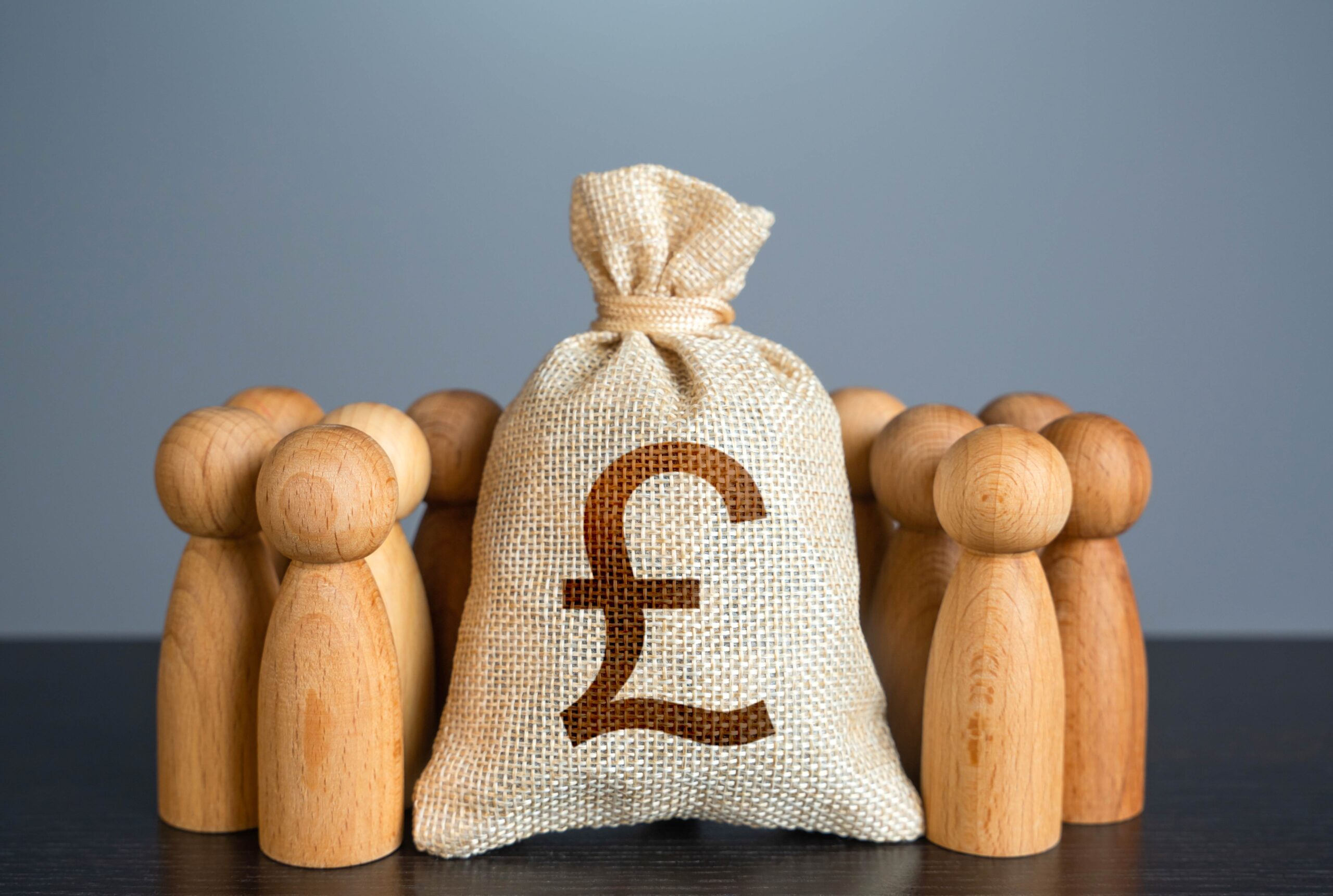 People figures stand around British pound sterling money bag.