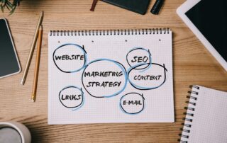 top view of business supplies, digital devices and notebook with marketing strategy on workplace